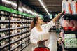 © Roman - Woman buys diapers for child at the supermarket, portrait of young mother in shop mall.
