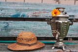 Fototapeta Sport - An old straw hat and a samovar stand on a bench