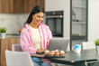 © ivanko80 - Young woman using laptop in kitchen
