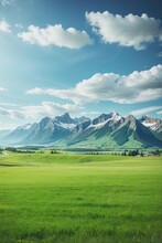 Panoramic Natural Landscape With Green Grass Field, Blue Sky With Clouds And Mountains In The Background