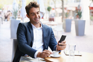 Canvas Print - Shes on the way....Shot of a young businessman reading a text while sitting at an outdoor cafe.