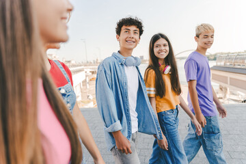 Beautiful, positive smiling multiracial college students walking together on urban street