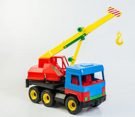 Multi-colored plastic toy trucks for children's games on a white background. Truck crane.