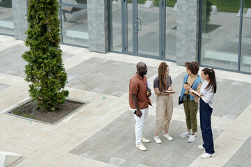 Leinwandbilder - group of young multicultural employees in casualwear discussing working points while standing in front of camera in urban environment
