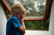 © kieferpix - sad child next to window on rainy day suffering loneliness, and a hint of happiness.
