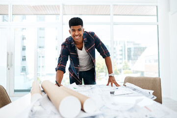 Canvas Print - At the head of the design helm. Portrait of a young man going over blueprints in a modern office.