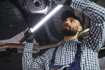 Wall Mural - Adult man in blue colored uniform works in the automobile salon.