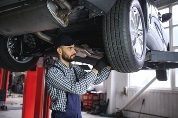 Leinwandbilder - Adult man in blue colored uniform works in the automobile salon.