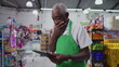 © Marco - Confused senior worker of supermarket using technology feeling frustration, scratching forehead while holding tablet device
