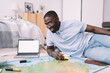 © BullRun - Black man with map and laptop in apartment