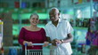© Marco - Happy diverse customers smiling inside grocery business store with shopping cart