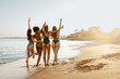 © Prostock-studio - Bikini fun. Group of diverse women in swimwear embracing and walking at the beach enjoying sunset, copy space, back view