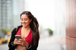 © mimagephotos - young smiling woman looking at mobile phone in city