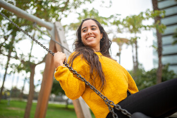 happy young woman swinging in the park