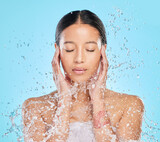 Fototapeta  - Skincare, water splash and face of woman in studio for wellness, healthy skin and cleaning. Bathroom, shower and female person with liquid for facial grooming, washing and beauty on blue background