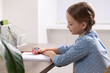 © New Africa - Girl erasing drawing in her book at wooden table in room