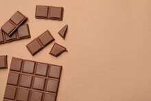 Pieces Of Delicious Chocolate Bar On Beige Background, Flat Lay. Space For Text