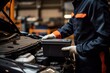 © sirisakboakaew - a car mechanic in a service center picking up a new battery to replace the car. for cars that use the service Replace the battery at the store