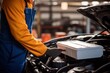 © sirisakboakaew - a car mechanic in a service center picking up a new battery to replace the car. for cars that use the service Replace the battery at the store