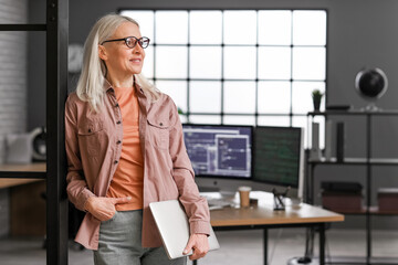 Wall Mural - mature female programmer working with laptop in office