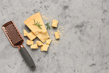 Pieces of tasty Parmesan cheese and grater on grunge background