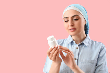 Wall Mural - Young woman after chemotherapy with bottle of pills on pink background