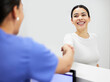 © Ismail/peopleimages.com - Handshake, nurse and woman at clinic reception, healthcare service and talking, questions or health consultation. Consulting, welcome and doctor or people at help desk for insurance survey or advice
