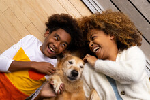Happy african american mother and son lying on floor with their pet dog