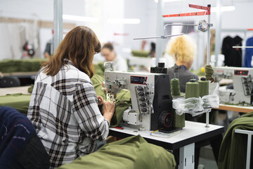 Wall Mural - workers in an industrial garment factory sew clothes on sewing machine