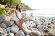 beautiful sexy girl in a short dress sits on the stones near the sea