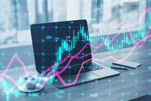 Close Up Of Laptop At Notebook With Coffee Cup And Glowing Forex Index Chart With Grid On Blurry Background. Market, Finance And Online Trading Concept. Double Exposure.