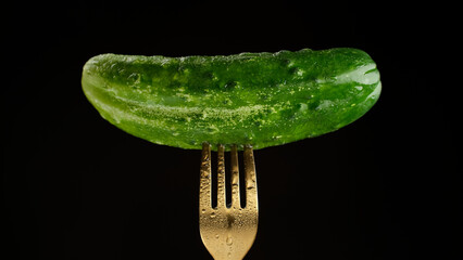 Poster - Fresh green cucumber on fork, isolated on black background