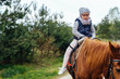 Little girl riding on a horseback. The girl is sitting on a horse . A child on a day walk on the ranch.