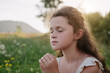 Close up of cute kid expresses his faith and devotion through prayer at sunset. Little Christian and happy in prayer. Preteen girl with closed eyes and folded hands he speaks to God with innocence