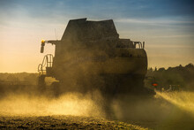 Combine Harvester Working In Wheat Field In The Evening