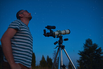 Wall Mural - astronomer looking at the starry skies with a telescope.