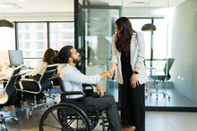 Disabled Businessman Shaking Hands With Businesswoman In Office