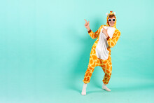 Young Funny Guy In Orange Giraffe Pajamas Dances At Party In Sunglasses And Points Back