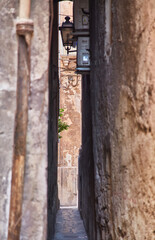 Wall Mural - Travel destination. Old street in city with road and stone buildings. Beautiful narrow street with paving stones in the old city.