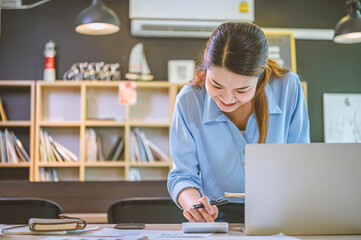 Wall Mural - Business asian woman sitting at a desk at an office By using the calculator to work. Business Concept Analysis and Planning.