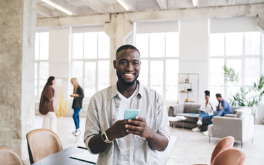 Sticker - Cheerful ethnic man with smartphone in office