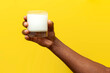 hand of african american man holds glass of milk on yellow isolated background
