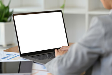 Wall Mural - Behind shoulder view image of businesswoman with suit outfit working with laptop computer, Empty screen of laptop banner or advertisement.