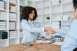 © Jirapong - The bank's Female African american Mortgage Officers shake hands with customers to congratulate them after signing a housing investment loan agreement