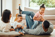 Happy family, laughing and playing on floor in living room for fun bonding relationship together at home. Father, mother and children enjoying funny play time, laugh or holiday weekend in the house