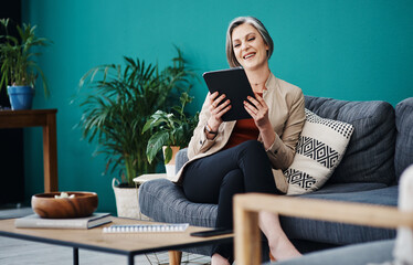 Wall Mural - The business seems to be doing well. Cropped shot of an attractive mature businesswoman sitting alone and using a tablet in her home office.