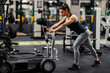 © Dusan Petkovic - Side view of muscular strong female bodybuilder pushing weights in a gym during her strength training.