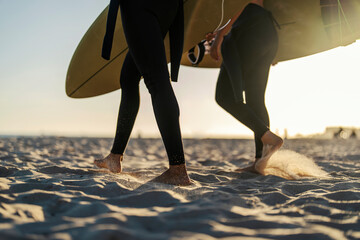 Wall Mural - Cropped picture of surfers' feet walking on the sand beach.