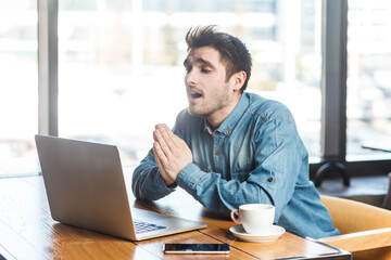 portrait of hopeful bearded man freelancer in blue jeans shirt working on laptop, having online meet