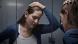Upset and stressed woman standing at mirror in bathroom. Concept of depression, suicide, stress, mental illness, loneliness and frustration.